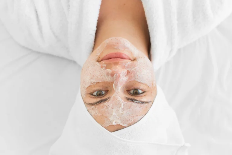 Profissional aplicando máscara facial em paciente durante a limpeza de pele na Clínica Essencial Estética