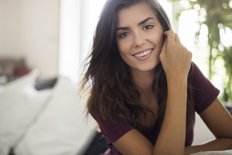 Mulher sorrindo discretamente ao se olhar no espelho com semblante de autoconfiança